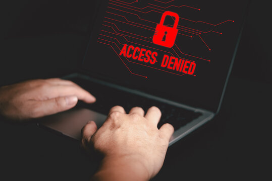 Hands typing on laptop with red Access Denied warning screen, concept of cybersecurity, hacking prevention, data breach alert, and online security protection.
