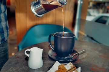 He pours filter coffee prepared with a French press into a cup
