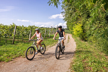 Couple riding e-bikes through vineyard path