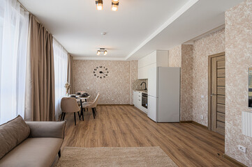 modern apartment interior featuring a cozy living area, dining set, and a functional kitchen. Warm tones and minimalist design create a welcoming atmosphere
