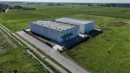 Modern data center building surrounded by green fields under a clear blue sky, providing cloud storage solutions, captured in a slow motion aerial view, slow motion shot - Powered by Adobe