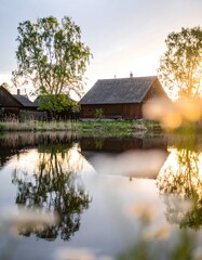 Obraz premium Rustic wooden houses reflected in a tranquil pond at sunset