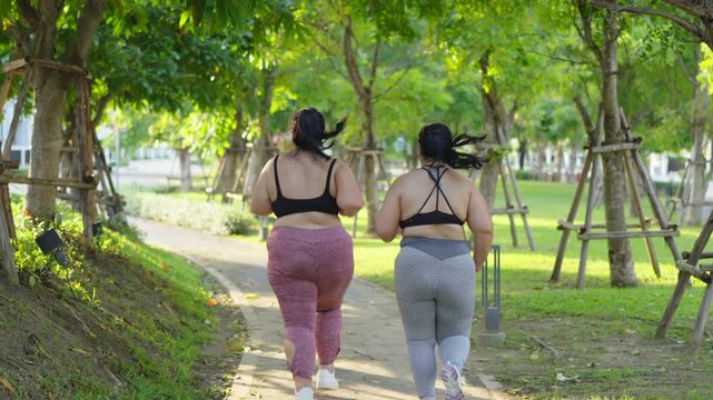 Back view chubby woman giving hi five and jogging in the park