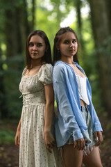 Portrait of beautiful young twin sisters in a summer forest.