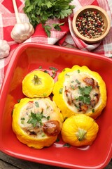 Tasty stuffed pattypan squashes in baking dish and spices on wooden table, flat lay