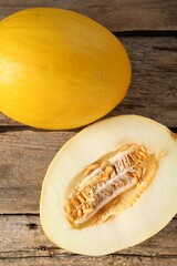 Cut and whole ripe melons on wooden table, top view