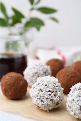 Delicious homemade candies with cocoa powder and coconut flakes on table, closeup