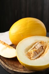 Cut and whole ripe melons on black wooden table, closeup