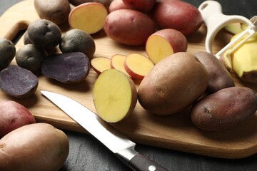Different types of potatoes, peeler and knife on black table, closeup