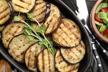 Grilled slices of eggplant with microgreens served on wooden table, closeup