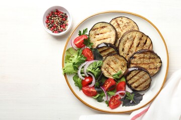 Grilled slices of eggplant with salad and peppercorns on white wooden table, top view