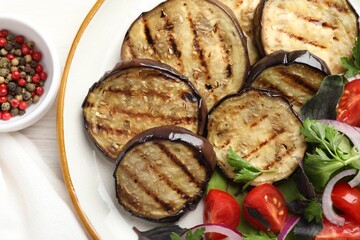 Grilled slices of eggplant with salad and peppercorns on white wooden table, top view