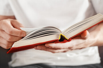 men's hands hold a red hardcover book