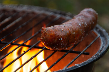Grilled pork sausage on fire on a summer evening, at a grill party in a backyard. Version 12.
