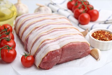 Piece of raw beef meat, tomatoes and spices on table, closeup