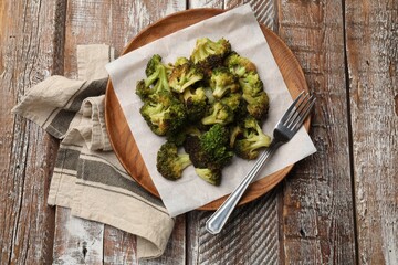 Tasty fried broccoli and fork on wooden table, top view