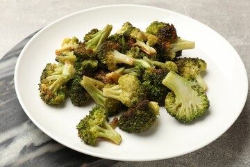 Tasty fried broccoli on light grey table, closeup