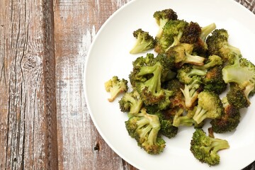 Tasty fried broccoli on wooden table, top view. Space for text