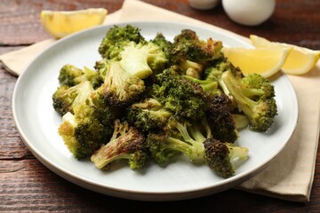 Tasty fried broccoli and lemon on wooden table, closeup