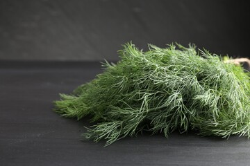 Bunch of fresh dill on black table, closeup. Space for text
