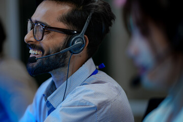 Close-up of a friendly male customer service agent smiling while talking on a headset. A concept for excellent support, job satisfaction, and a positive client communication experience.