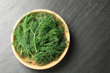 Fresh dill in bowl on black table, top view. Space for text