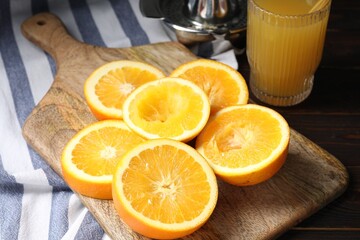 Freshly squeezed orange juice, fruits, juicer and towel on wooden table, closeup