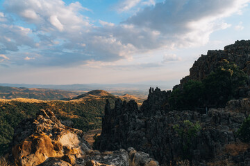 A mountain range with a cloudy sky in the background. The sky is a mix of blue and white clouds