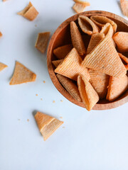 Crispy cone-shaped snacks in a wooden bowl, isolated on a white background with ample copy space. A delicious savory appetizer concept.