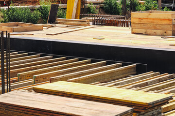 Construction site with wooden planks and formwork. Building materials prepared for concrete foundation work. Structural framework in progress. Industrial construction elements for architecture.