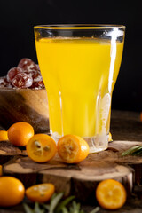citrus-flavored orange juice and fresh kumquat fruits on a wooden table, delicious and fresh orange juice and fresh kumquat fruits next to a glass