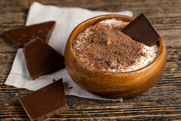 sweet yogurt in a wooden bowl with chocolate crumbs, chocolate pieces in milk yogurt, sweet dessert with chocolate flavor