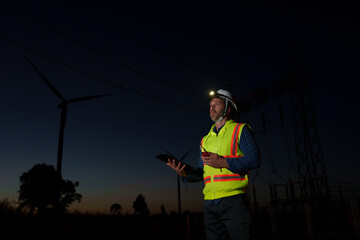 Engineers surveying the power generation at a wind farm, natural energy, industry and environment, clean energy at night