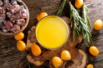 citrus-flavored orange juice and fresh kumquat fruits on a wooden table, delicious and fresh orange juice and fresh kumquat fruits next to a glass