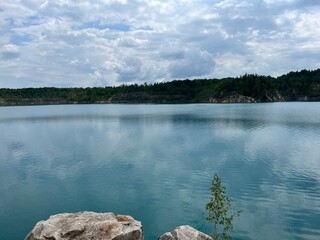 Scenic lake with calm turquoise water reflecting sky and clouds surrounded by green forest hills