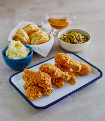 Southern buttermilk fried chicken drumsticks with biscuits, mashed potato, and collard greens