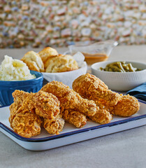 Southern buttermilk fried chicken drumsticks with biscuits, mashed potato, and collard greens
