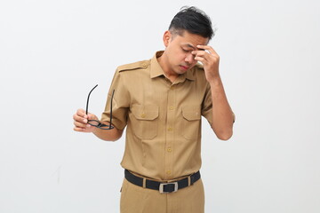 Tired Indonesian civil servant worker holding eyeglasses and suffering from headache