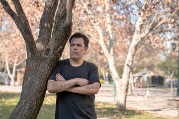 Man leaning on tree looking up in park