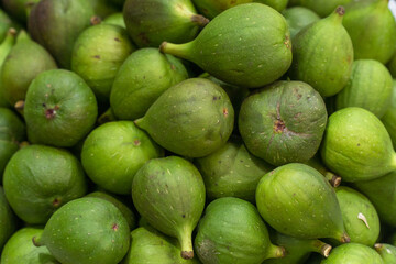 Close-up of fresh brevas (early figs) with green skin at a market stall.