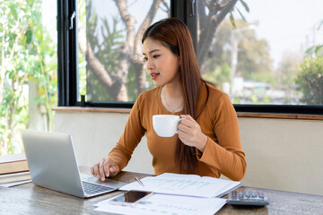 Businesswoman working while enjoying coffee.
