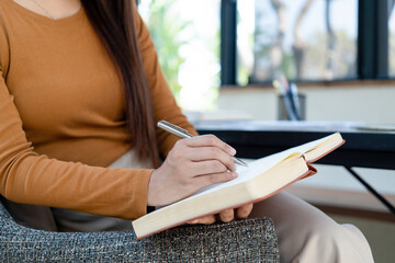 Young woman engages in note-taking at workspace.