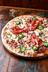 Pizza with salami, mozzarella cheese and jalapeno pepper. Wooden background. Soft focus. Copy space. .	