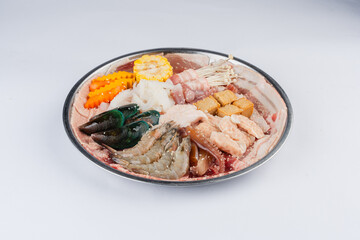 Assorted seafood and meat platter with vegetables on a round metal dish. Top view.