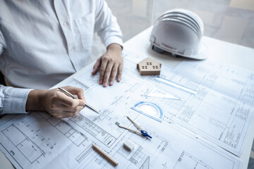 Architects or engineering working on objects tools and construction planning new architectural project on blueprint and model house in modern office