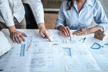 Team of architects or engineering consulting and analyzing working on objects tools and construction drawings inspection, discussing planning new architectural project on blueprint and model house