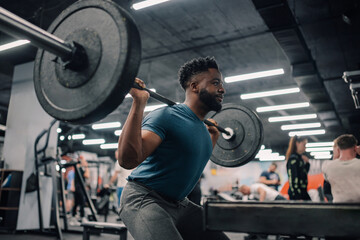Determined bodybuilder lifting weights, performing squats in gym