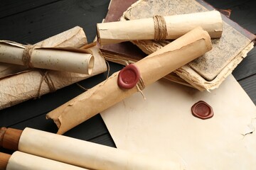 Many old rolled scrolls on black wooden table, closeup