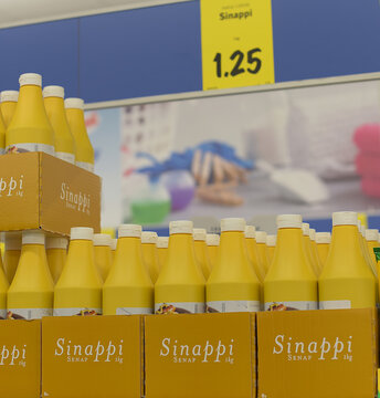 supermarket shelves with yellow plastic bottles of 1 kg mustard.  