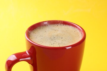 Aromatic coffee in cup on yellow background, closeup